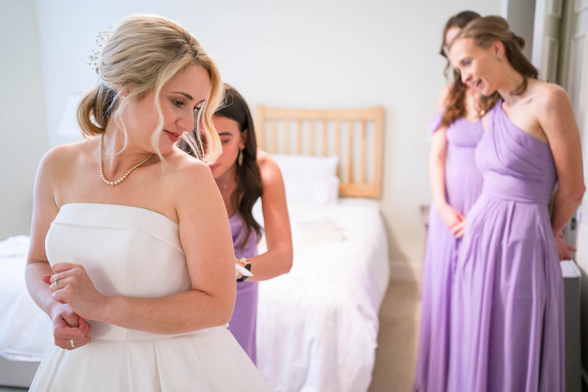 Hollie's bridesmaids helping her get into her wedding dress
