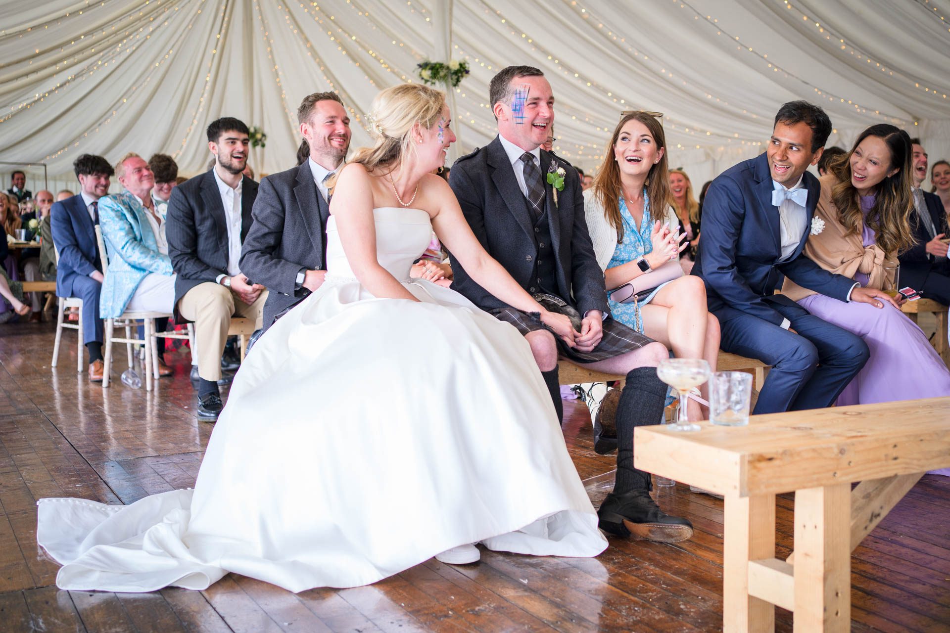 Groom and guests laughing at the best man's speech