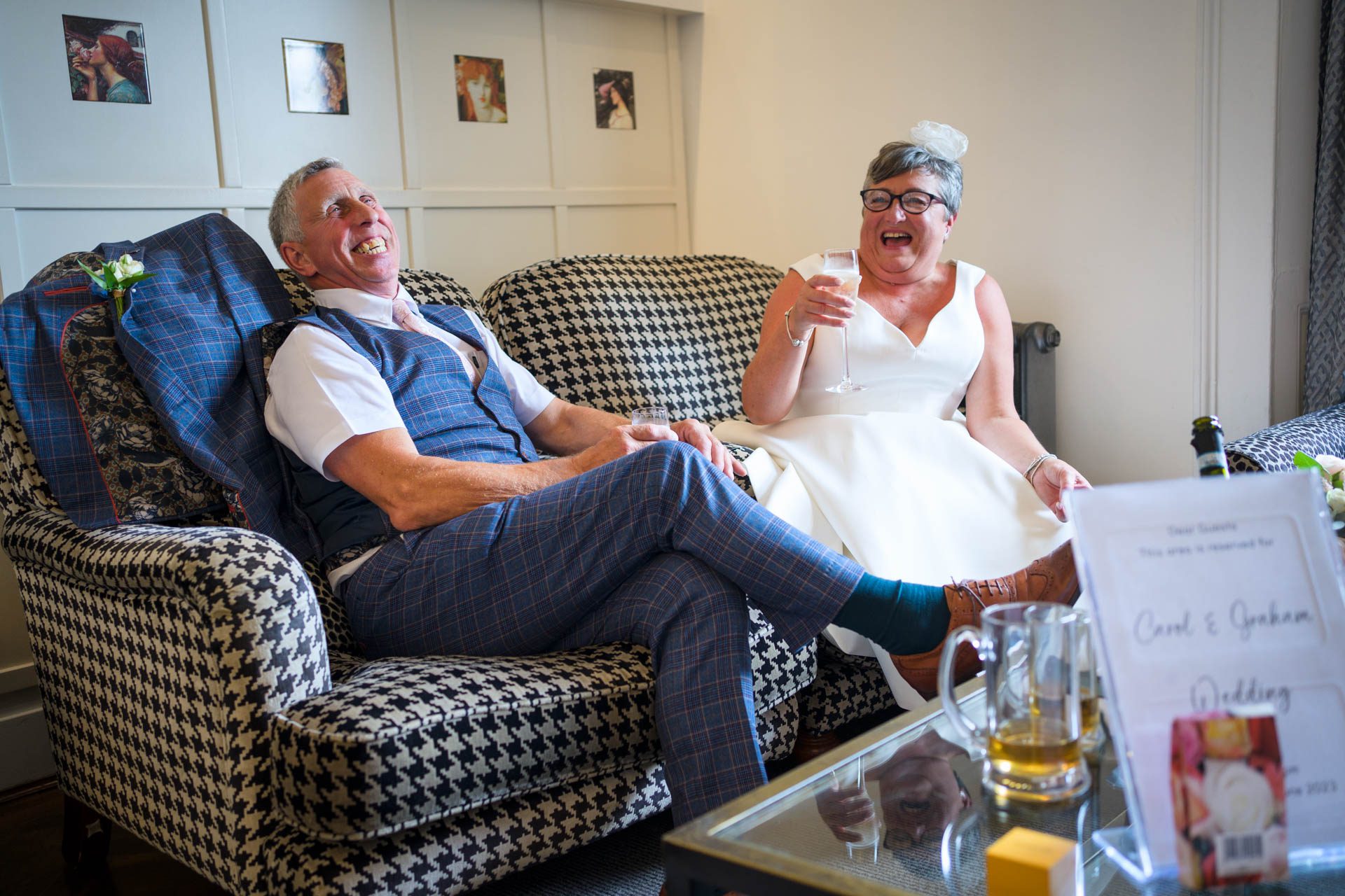 Bride and groom laughing whilst sitting on sofa in bar of Low Wood Bay Resort and Spa