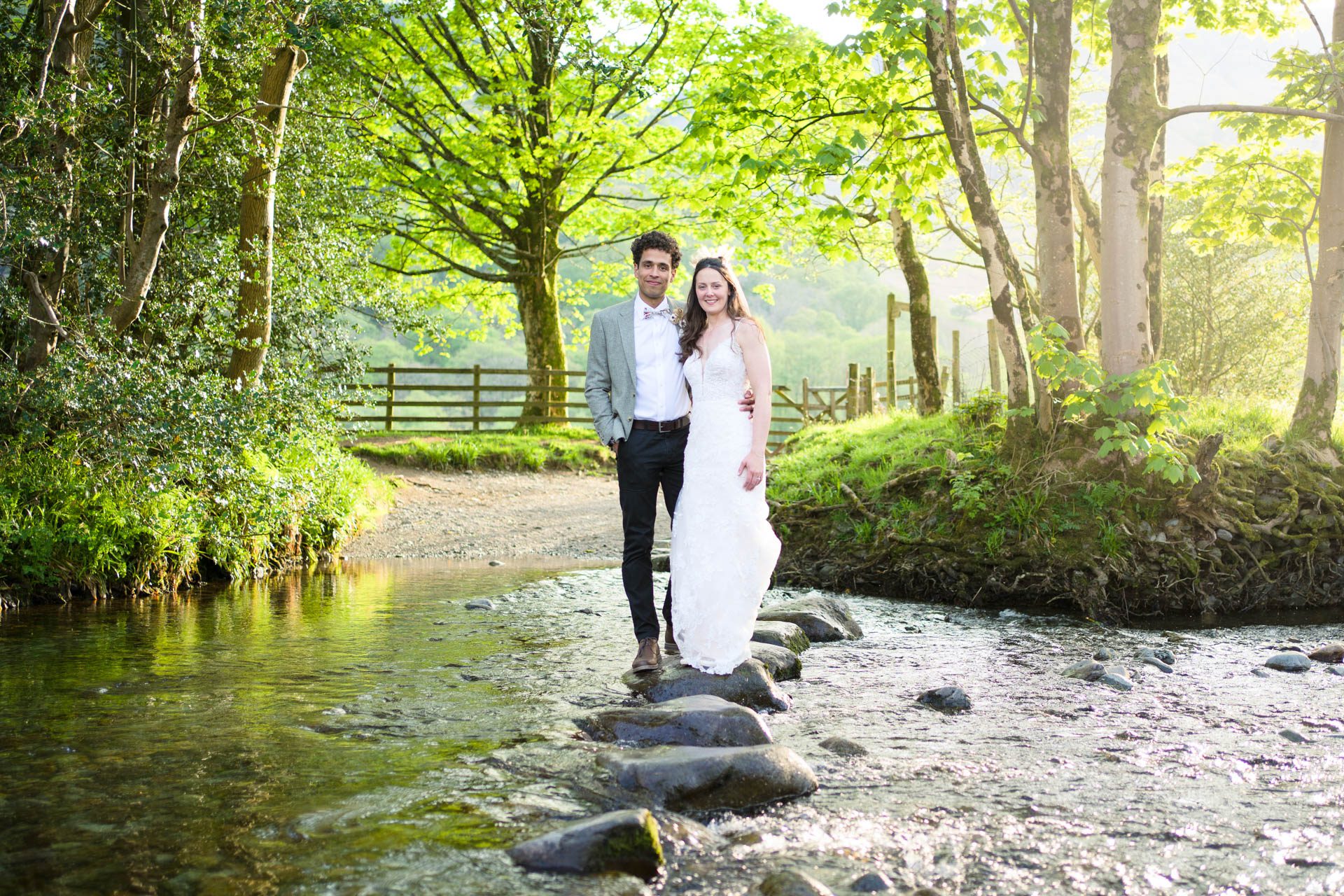 A Borrowdale Wedding Portrait. Bride and groom standing on stepping stones